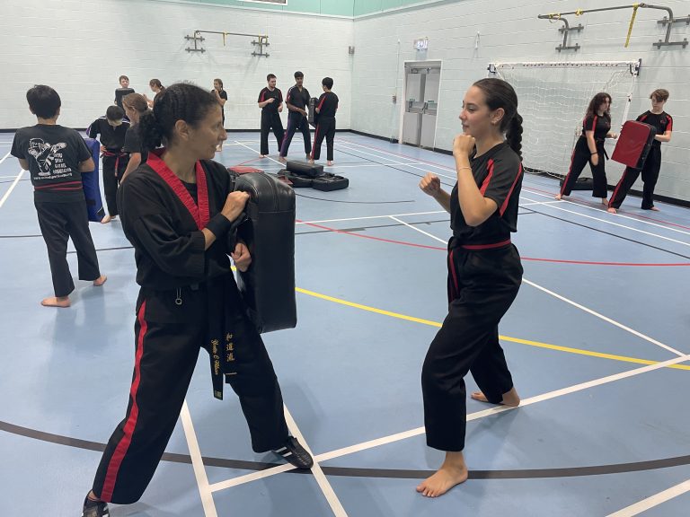 Instructor holding a pad for a student in the sports hall