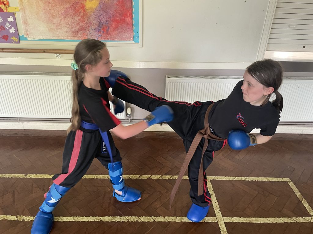 Two girls sparring in a karate class