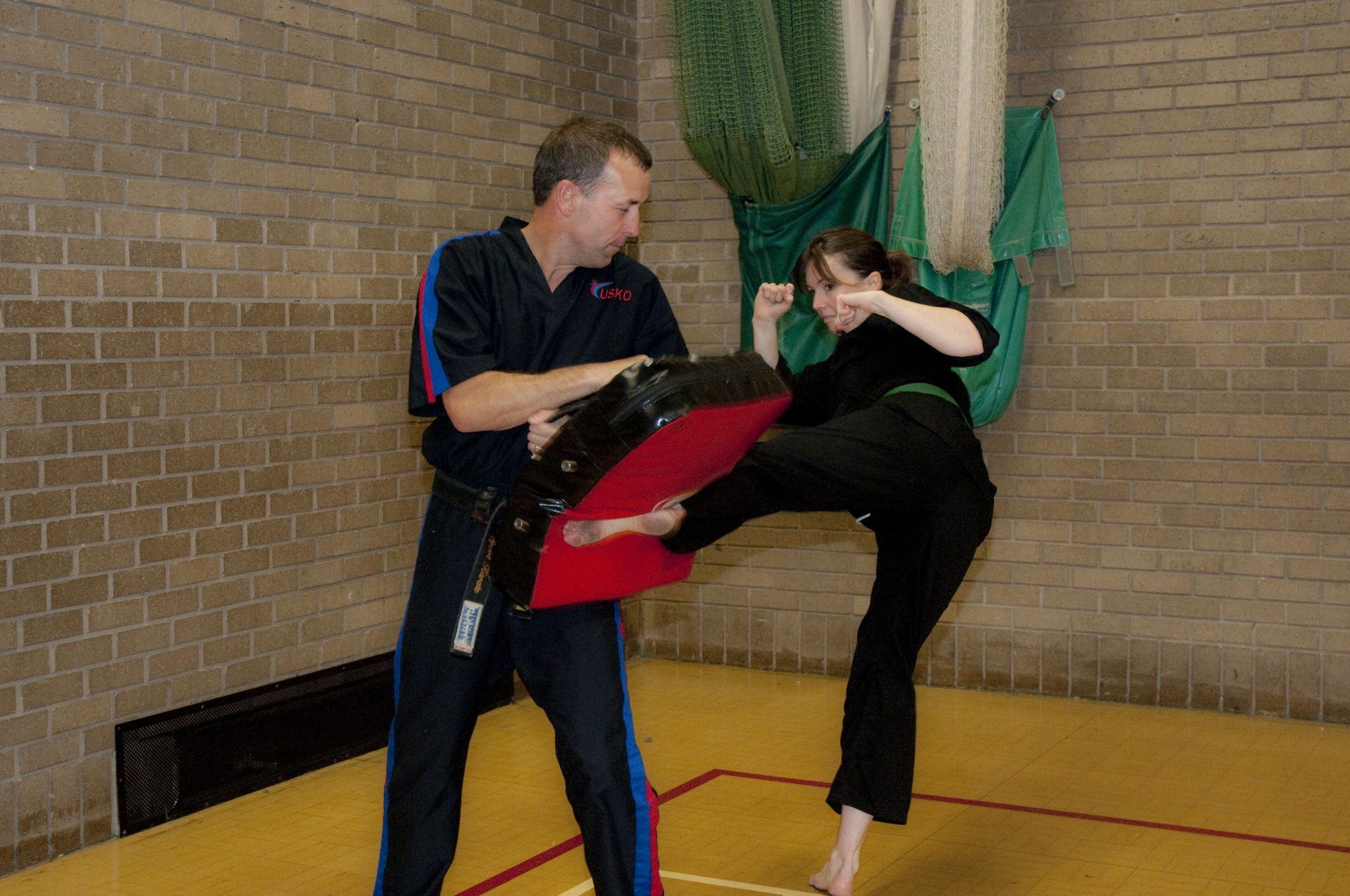 Student kicking a pad held by an instructor